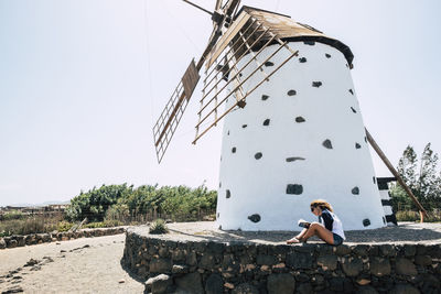 Side view of woman sitting against traditional windmill