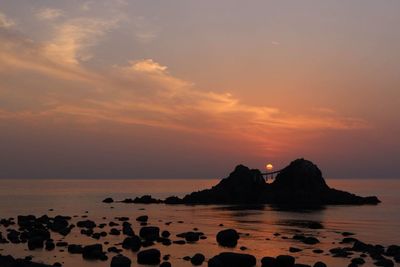 Rocks in sea at sunset