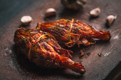 High angle view of chicken meat with garlic cloves served on wooden tray