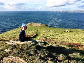 Portrait of girl sitting on rock formation by sea