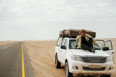 Side view of man riding motorcycle on road against sky