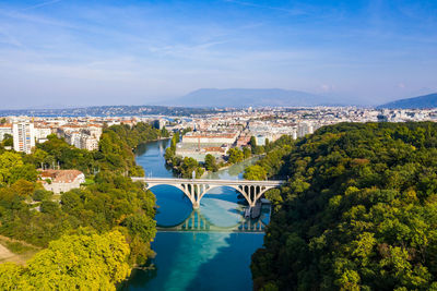 Aerial view of arch bridge over river amidst trees in city