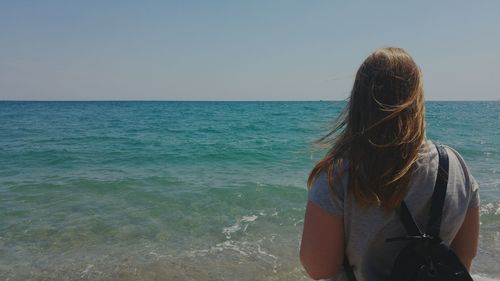 Rear view of woman standing in sea against sky