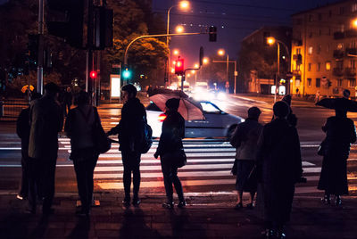 Full length of people standing on street in city at night