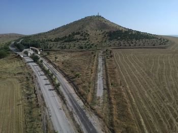 Panoramic view of road amidst field against clear sky