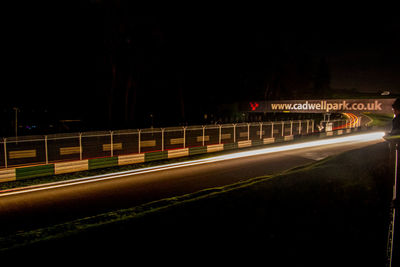 Light trails on road against sky at night