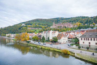 Buildings by river against sky