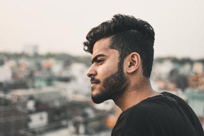 Young man looking away in city