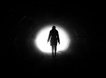 Full length rear view of woman walking in tunnel