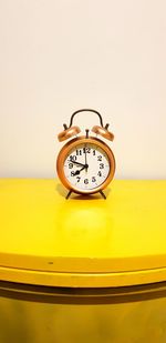 Close-up of clock on table against wall