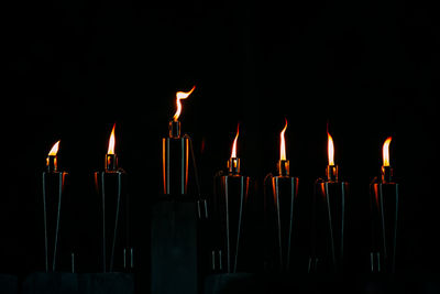 Close-up of burning candles against black background