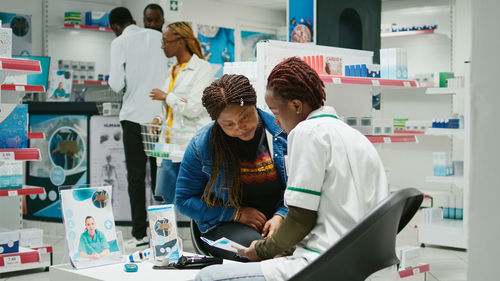 Side view of young woman using digital tablet while standing in office