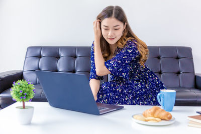 Young woman using phone while sitting on sofa