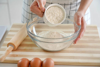 Close-up of woman hands pouring the flour into the bowl. increasing price of wheat, flour and bread.