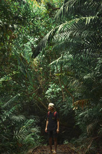 Full length of woman standing by tree in forest