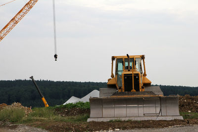 Earth mover at construction site against sky