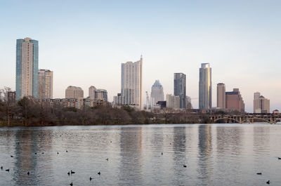 River by city skyline against clear sky