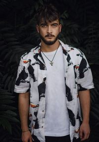 Portrait of handsome young man standing against plants