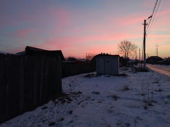 Snow covered landscape against sky during sunset