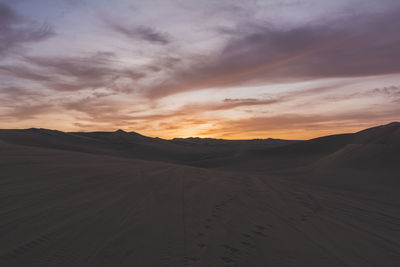 Footprints and tire tracks on sand in desert