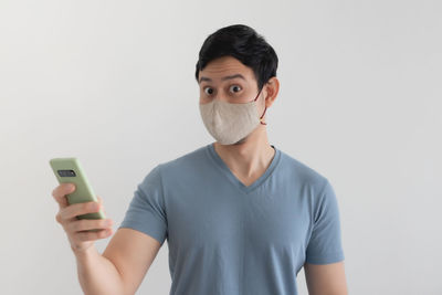 Portrait of mid adult man using smart phone against white background