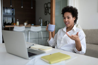 African american freelancer with mug during virtual meeting