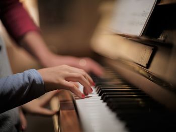 Cropped hand of woman playing piano at home