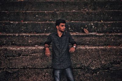 Portrait of young man standing against brick wall