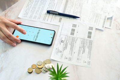 Cropped hand of woman using calculator on table