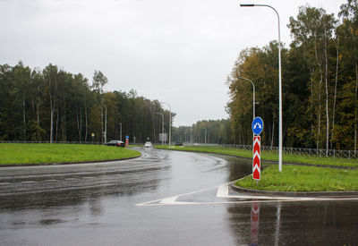 Road by trees in city during rainy season