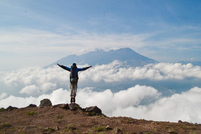 Man standing on rock against mountain range against sky