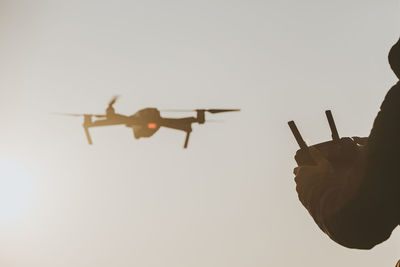 Low angle view of hand holding airplane against clear sky