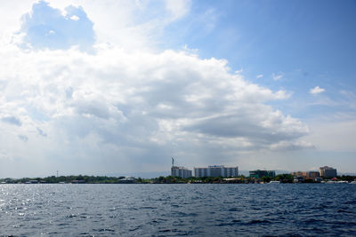 Buildings by sea against sky