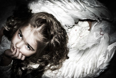 High angle portrait of cute girl in fairy costume sitting at home