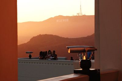 Coin-operated binoculars and people at griffith park observatory in front of hollywood text on mountain