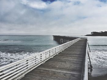 View of jetty in calm sea against cloudy sky