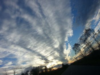 Low angle view of power lines against cloudy sky