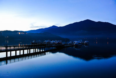 Boats moored in lake at dusk