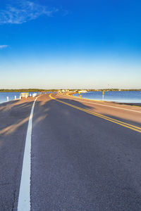 Road by sea against blue sky