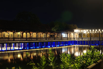 Illuminated bridge over river at night