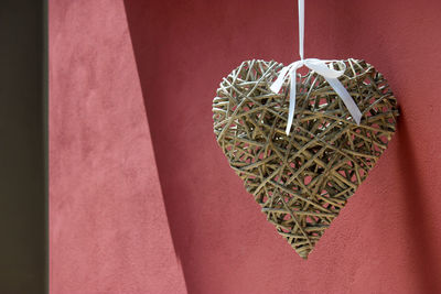 Close-up of heart shape decoration hanging red wall