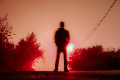 Rear view of silhouette man standing against sky during sunset