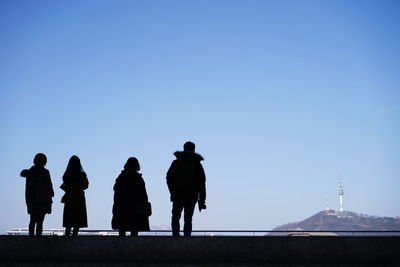 Rear view of silhouette people standing against clear blue sky