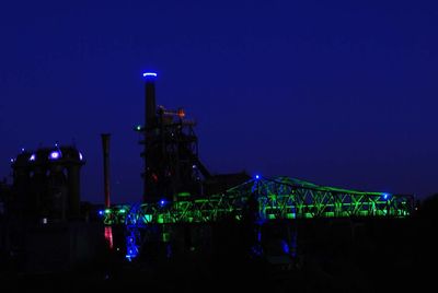 Illuminated factory against blue sky at night