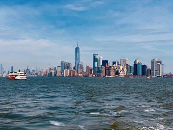 Sea by modern buildings in city against sky