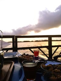 Table by sea against sky during sunset