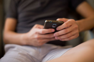 Midsection of man using phone while sitting on chair