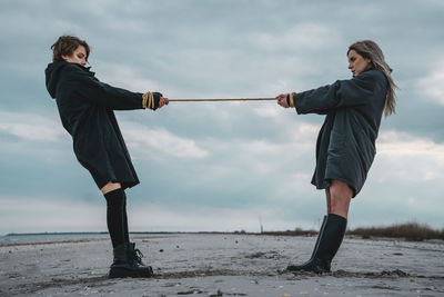 Full length of friends standing on land against sky