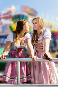 Young female friends standing at amusement park
