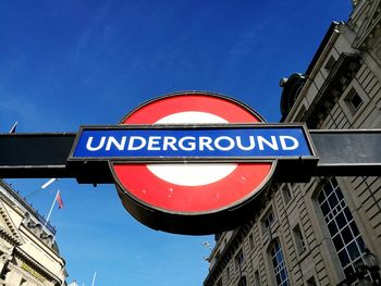 Low angle view of road sign against clear blue sky